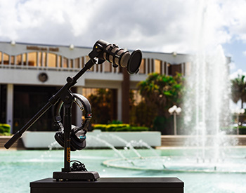 An audio equipment arrangement with a microphone stand and headphones, positioned in front of the reflecting pond.